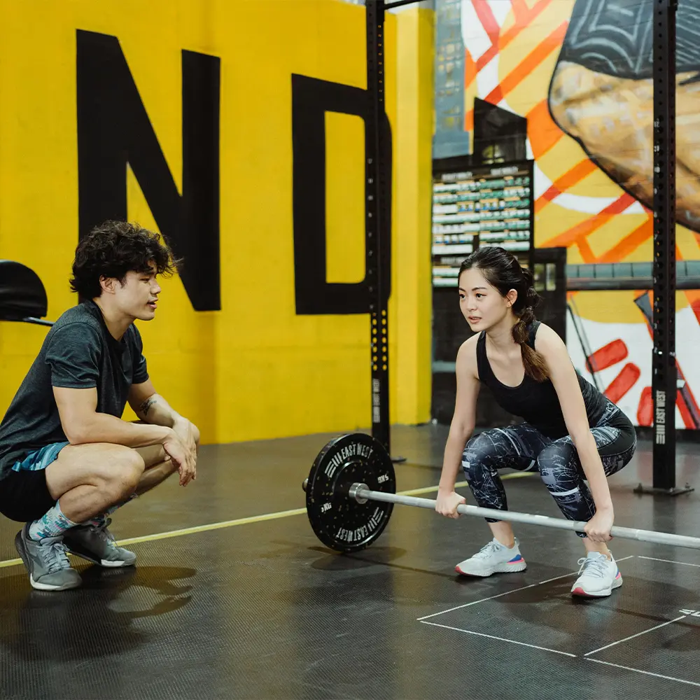 Personal Strength trainer working with client in gym